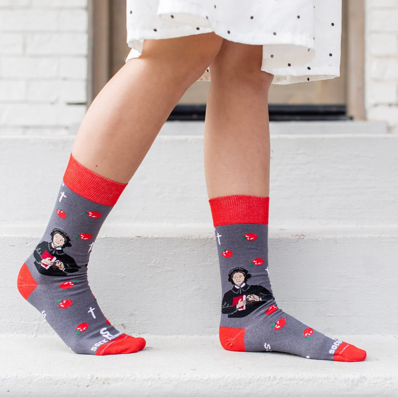 Person wearing red and gray sock featuring pictures of apples and St. Elizabeth Ann Seton