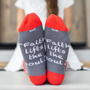Person wearing red and gray sock featuring pictures of apples and St. Elizabeth Ann Seton