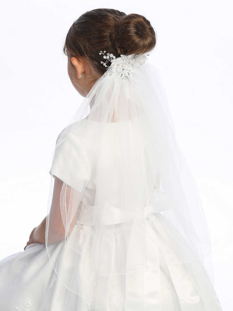 Side view on the floral details of a little girl's white sheer First Communion veil