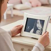 Girl holding an ivory and silver First Communion picture frame for a 3.5 x 5 inch size photo.
