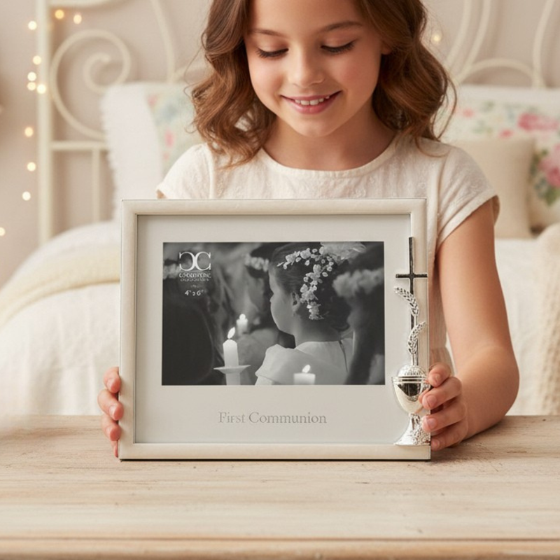 Young girl holding a First Communion picture frame for a 4x6 inch size photo on a wood table.