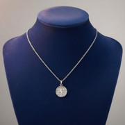 Silver necklace with a pendant on a blue mannequin bust against a gray background