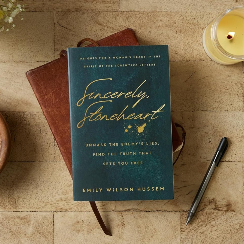 A dark green book with text 'Sincerely Stoneheart' on a wood desk.