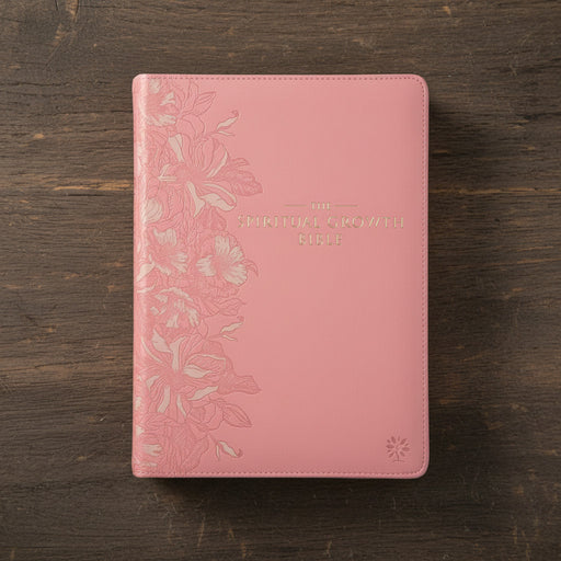 Pink bible with floral embossing on a wooden surface