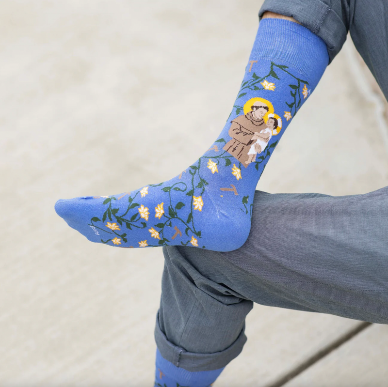A person wearing blue crew socks featuring an image of St. Anthony of Padua holding the Infant Jesus