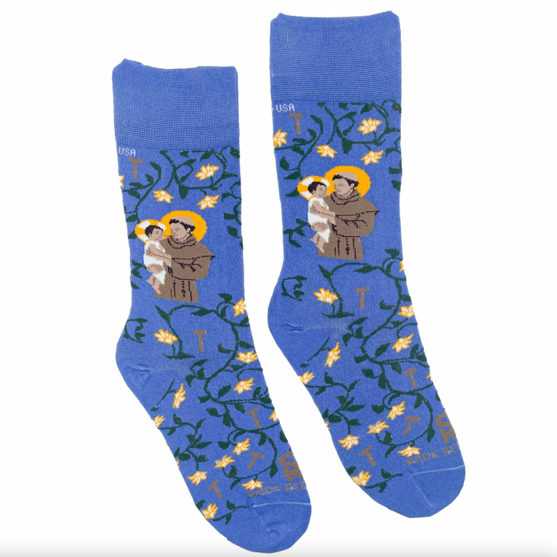 A pair of blue socks with a design featuring St. Anthony holding the Infant Jesus, surrounded by a floral pattern.