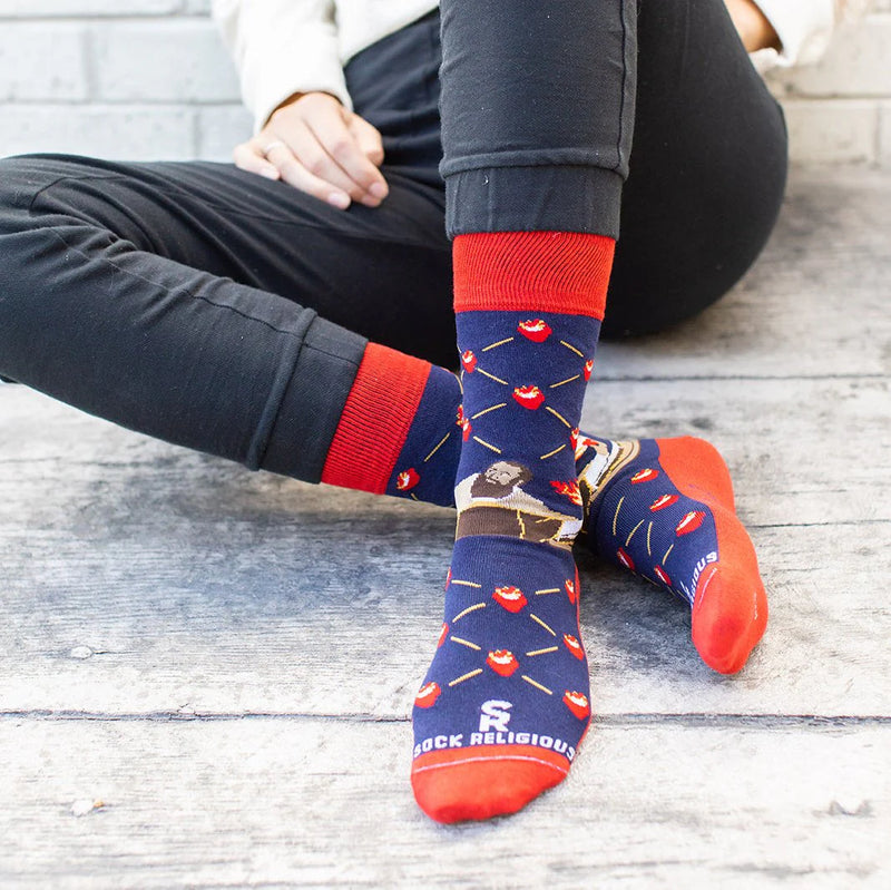 Person wearing blue and red patterned socks with St. Augustine and flaming hearts, on a wooden floor.