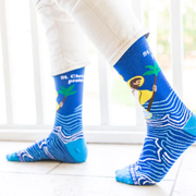 Person wearing blue socks with images of St. Christopher carrying the Infant Jesus through water