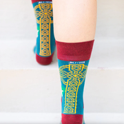 Person wearing teal and orange socks featuring an image of St. Dymphna
