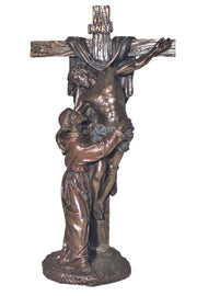A bronze statue depicting St. Francis of Assisi in a embrace with Christ crucified on a cross, both figures slightly angled towards the viewer.