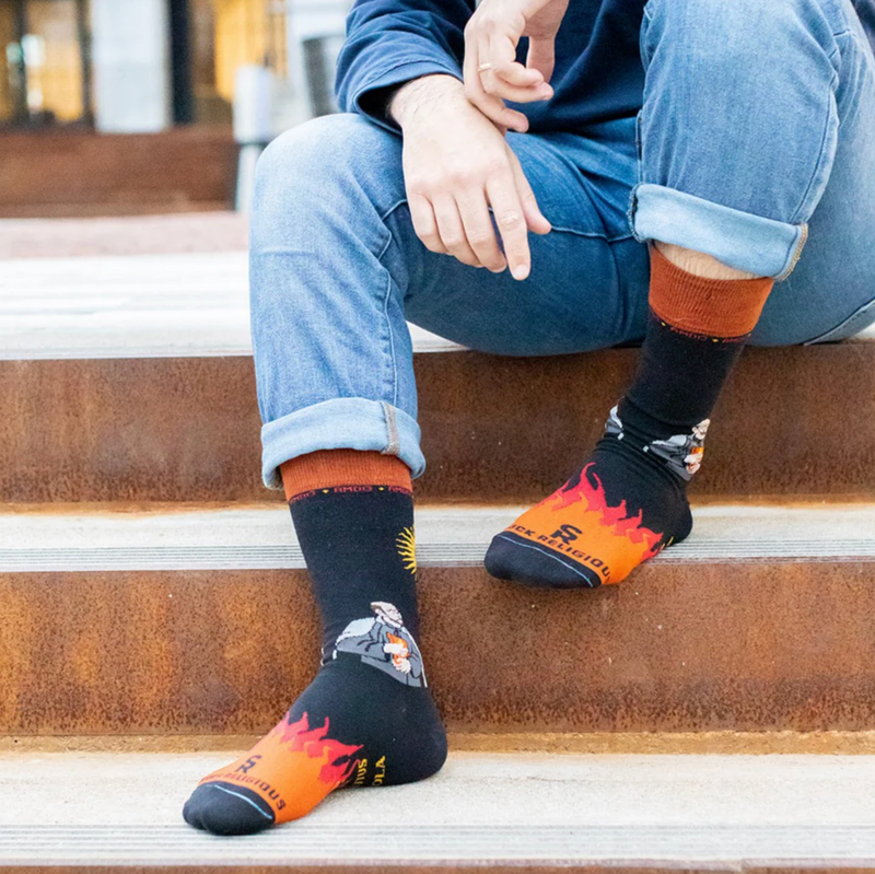 Person wearing black and orange socks featuring St. Ignatius of Loyola
