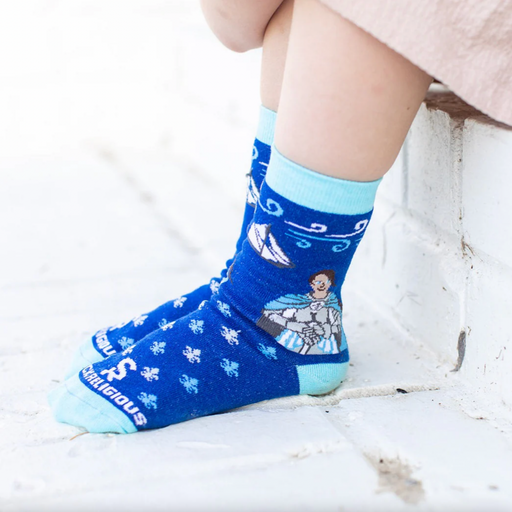 Child wearing blue crew socks featuring a fleur-de-lis pattern and an image of St. Joan of Arc holding a sword