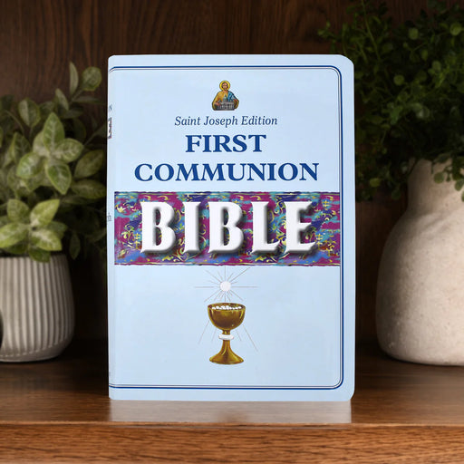Saint Joseph Edition First Communion Bible on a wooden surface with plants in the background
