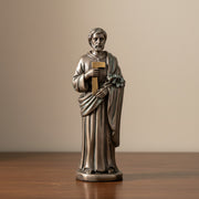 Bronze statue of St.Joseph the Worker holding a lily on a dark wood surface