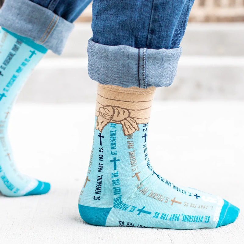 Light blue St. Peregrine-themed socks with text and cross designs worn with rolled-up jeans