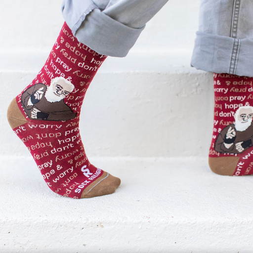 Person wearing red socks featuring an image of St. Padre Pio and text 'pray, hope, & don't worry'