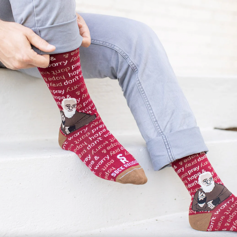 Person wearing red socks featuring an image of St. Padre Pio and text 'pray, hope, & don't worry'