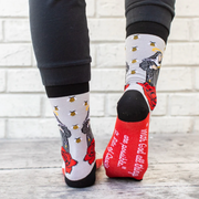 Person wearing gray socks with vibrant red roses and an image of St. Rita holding a cross.