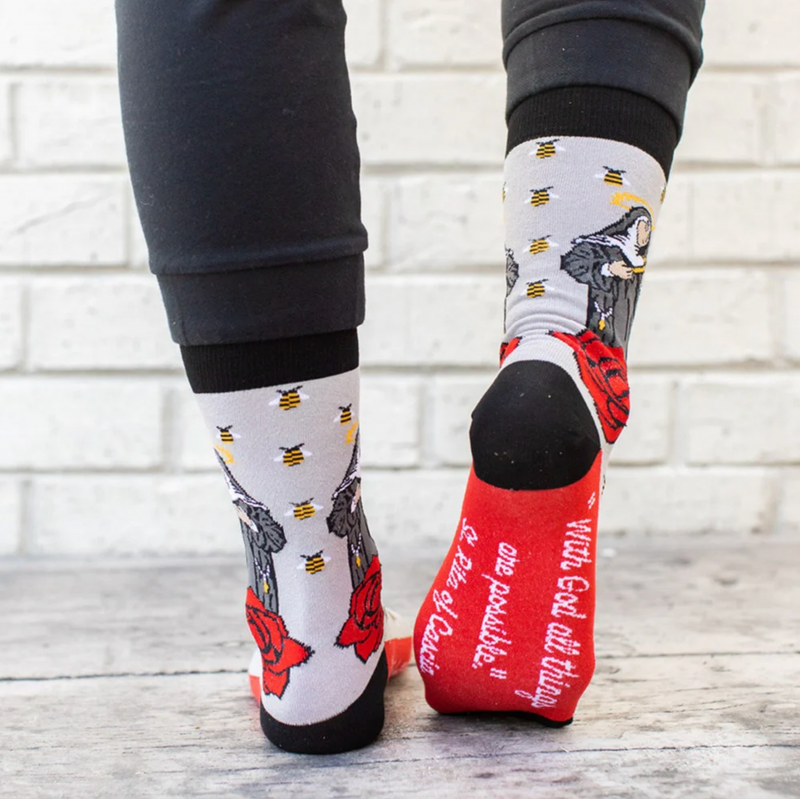 Person wearing gray socks with vibrant red roses and an image of St. Rita holding a cross.