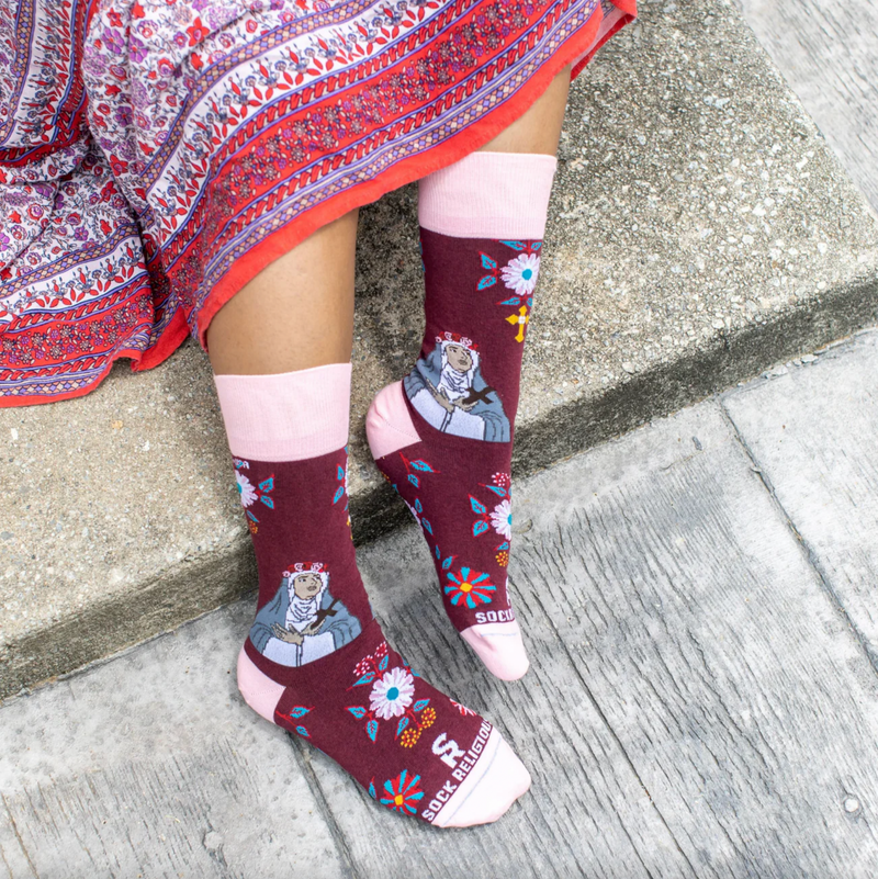 Person wearing burgundy and pink floral crew socks with an imagine of St. Rose of Lima.