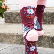Person wearing burgundy and pink floral crew socks with an imagine of St. Rose of Lima.
