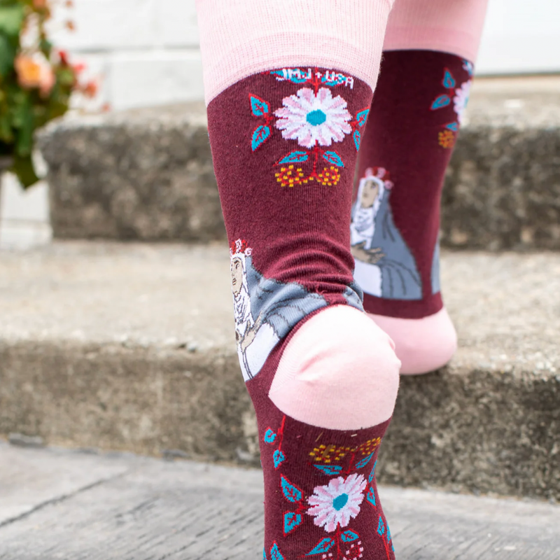 Person wearing burgundy and pink floral crew socks with an imagine of St. Rose of Lima.