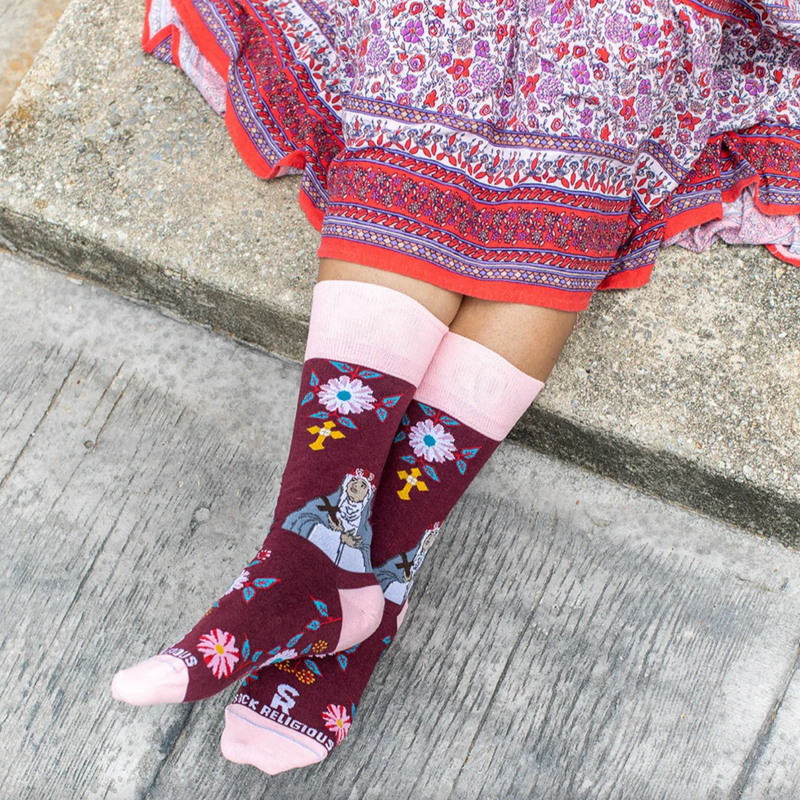 Person wearing burgundy and pink floral crew socks with an imagine of St. Rose of Lima.