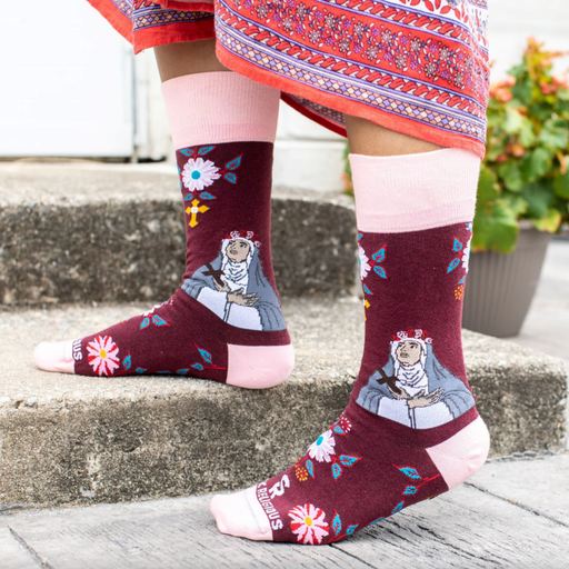 Person wearing burgundy and pink floral crew socks with an imagine of St. Rose of Lima.