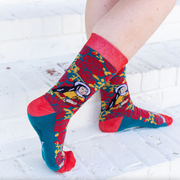 Person wearing red and yellow floral rose socks featuring an image of St. Therese the Little Flower