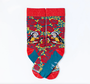 Person wearing red and yellow floral rose socks featuring an image of St. Therese the Little Flower