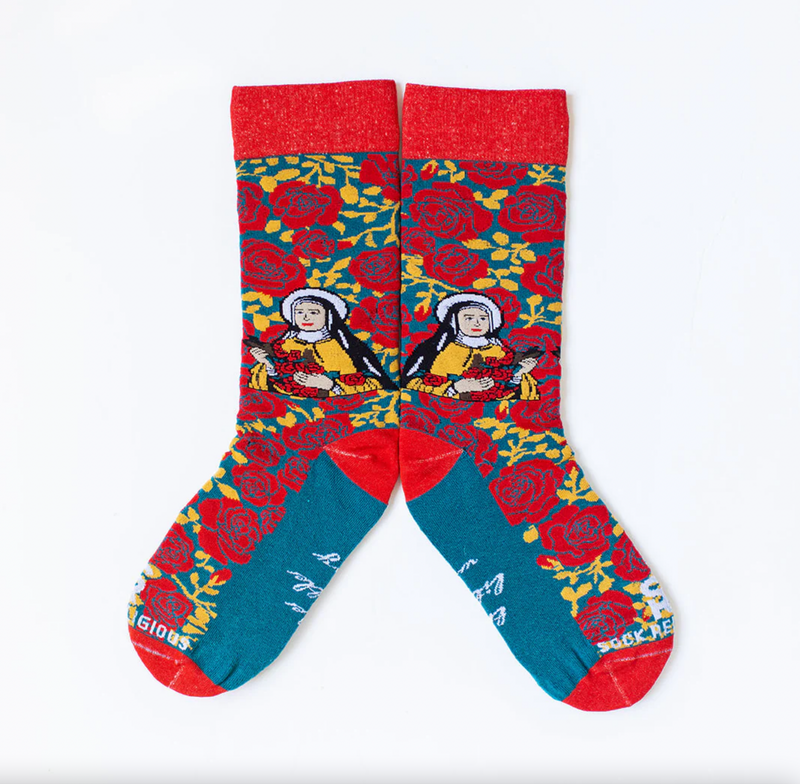 Person wearing red and yellow floral rose socks featuring an image of St. Therese the Little Flower