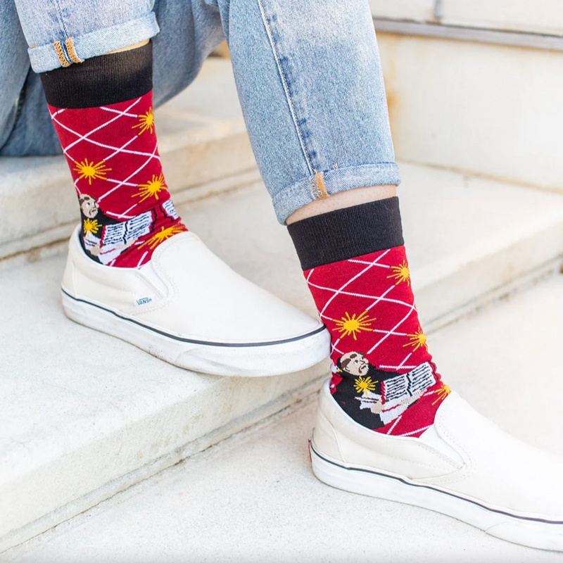 Person wearing bright red socks with an image of St. Thomas Aquinas holding an open book
