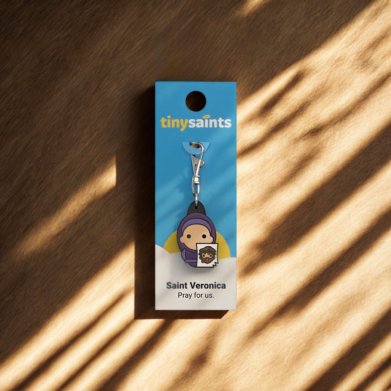 Keychain packaging with 'tiny saints' branding on a wooden surface