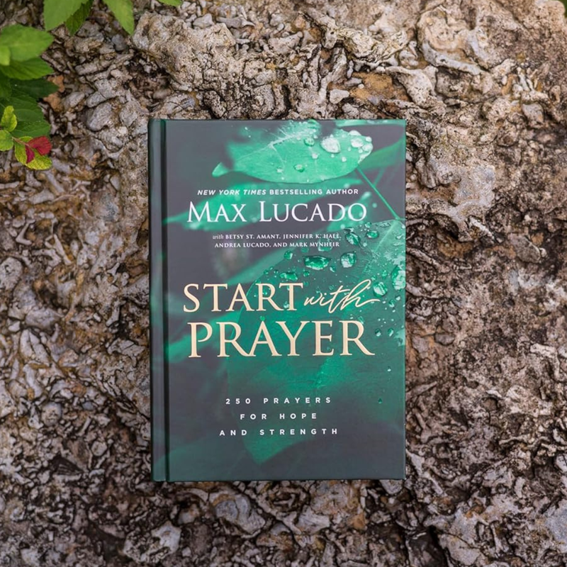 Book titled 'Start with Prayer' by Max Lucado on a textured stone surface.