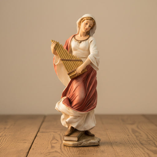 Statue of St. Cecilia playing a flute on a wooden surface with a beige background