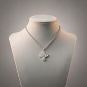 Silver necklace with a cross pendant on a mannequin bust against a gray background