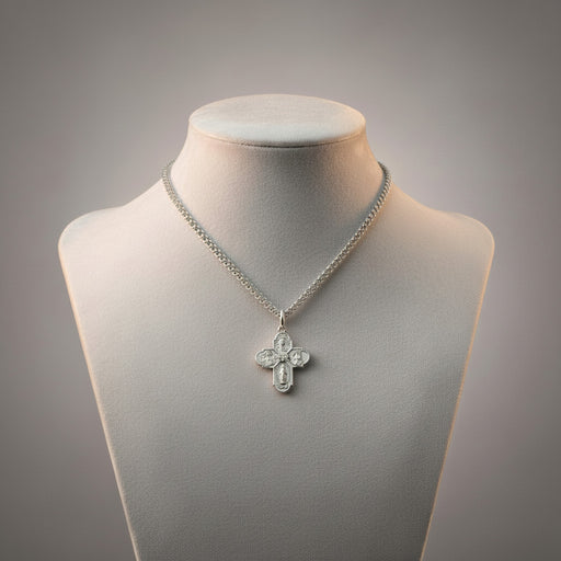 Silver necklace with a cross pendant on a mannequin bust against a gray background