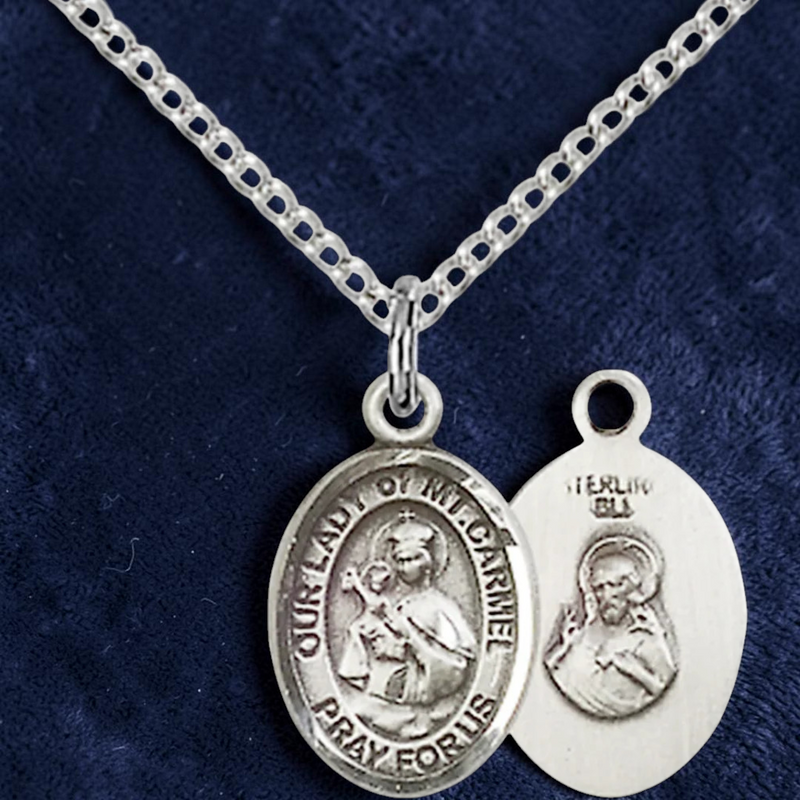 Silver religious pendant necklace on a blue fabric background