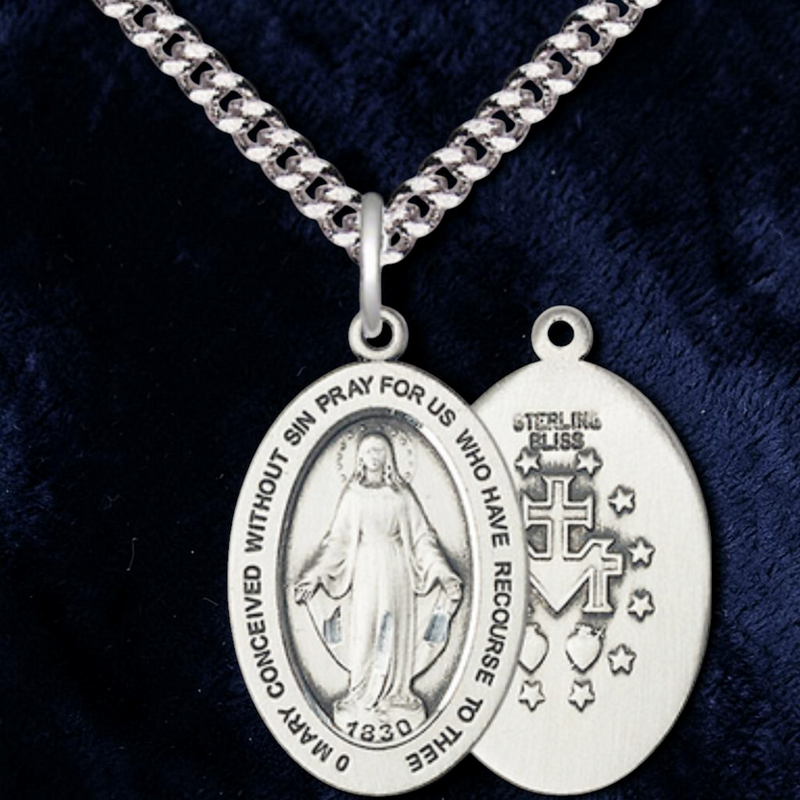 Silver religious medallion on a chain against a dark background