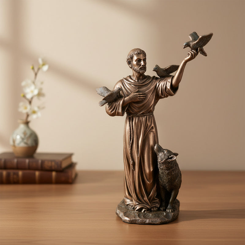 Bronze statue of a religious figure holding doves and a lamb on a wooden surface with a neutral background.
