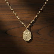 Gold St. Francis of Assisi necklace and chain on a wood surface