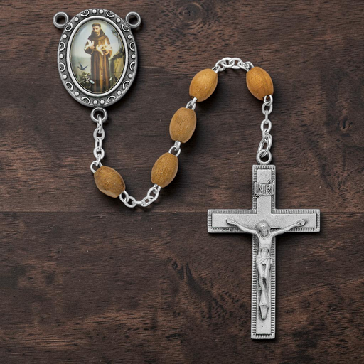 Rosary with wooden beads and silver cross on a wooden surface