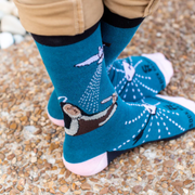 Person wearing blue socks featuring an image of St. Teresa of Avilia and the Holy Spirit