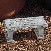 Memorial bench with engraved text on a gravel surface