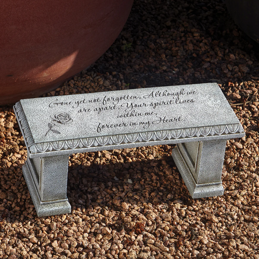 Memorial bench with engraved text on a gravel surface