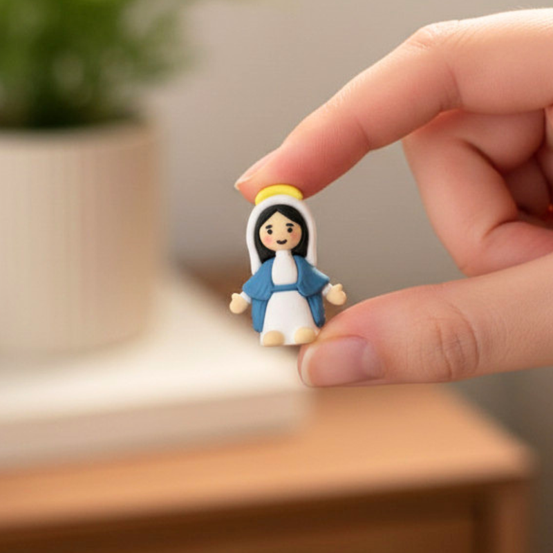 A tiny rubber figurine of the Virgin Mary held by two fingers.
