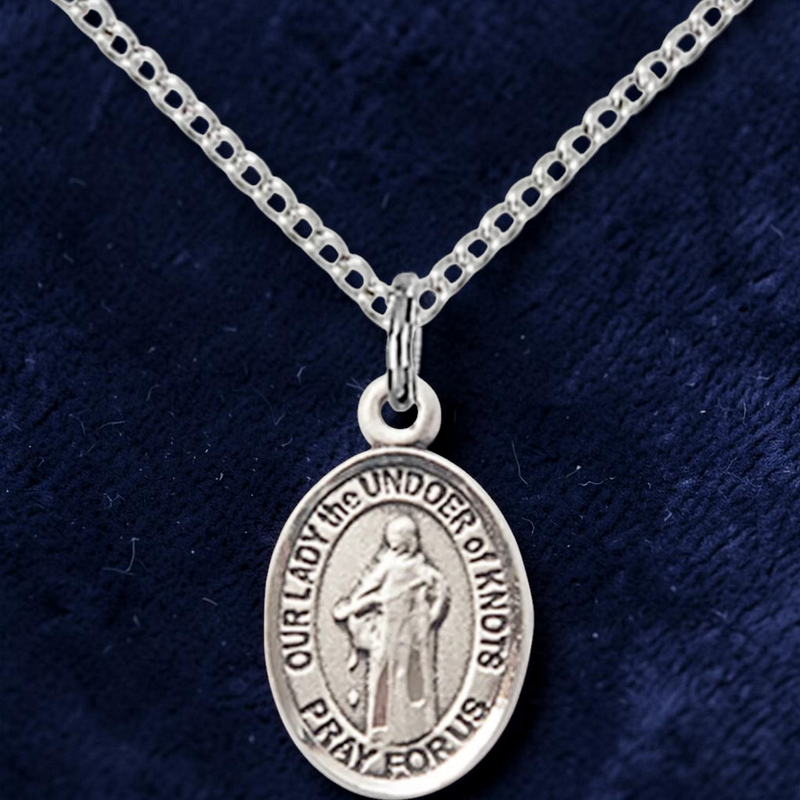 Silver pendant necklace on a dark blue fabric background