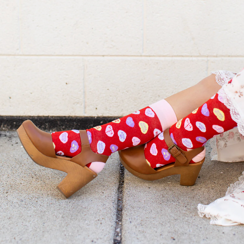 Person wearing red socks with red candy hearts and witty Christian puns
