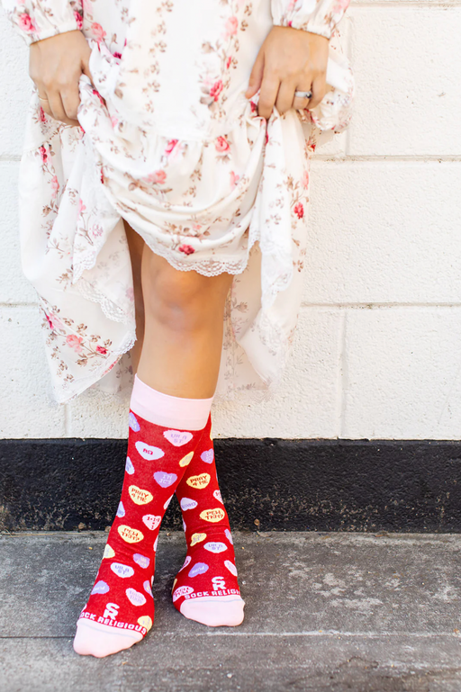 Person wearing red socks with red candy hearts and witty Christian puns