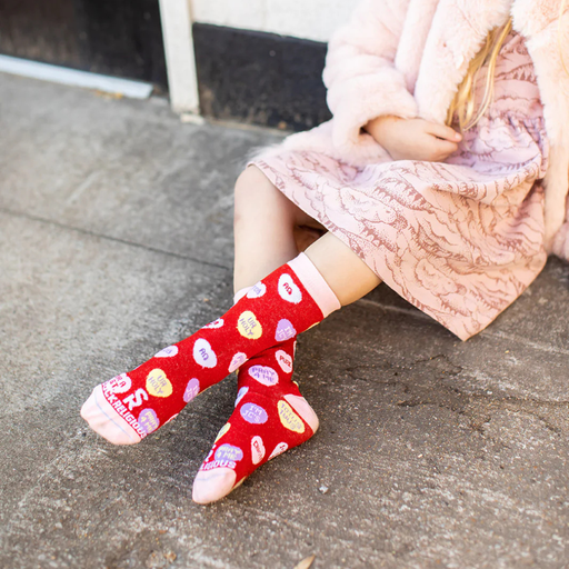 Child wearing red socks with candy hearts featuring witty Christian sayings
